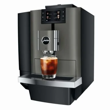 JURA X10 Dark Inox Kaffeevollautomat in Schrägansicht mit Farbdisplay und einem Glas Iced Coffee auf der Abtropfschale