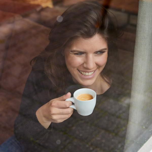 Frau trinkt ihren Kaffee am Fenster